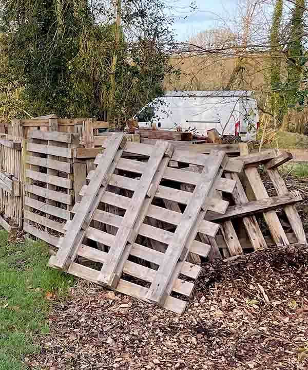 compost piles at the bottom of a sloping community garden