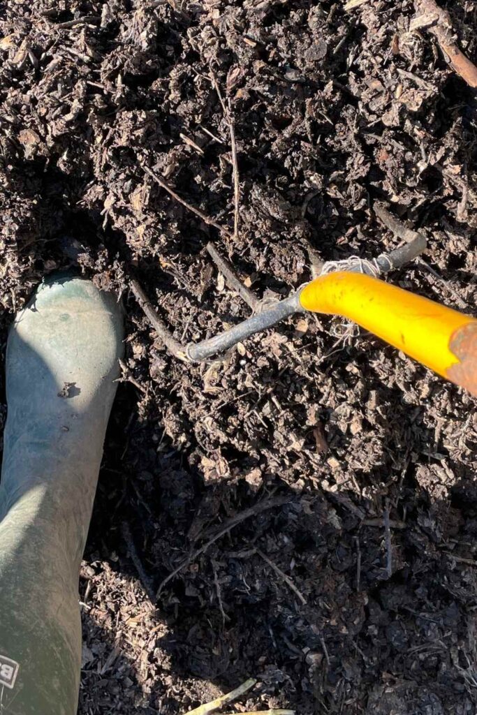 photo of a wellington boot and pitchfork in a compost pile