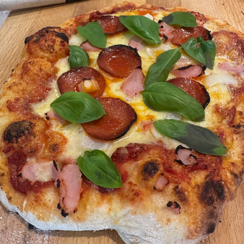 A rustic pizza with frish basil leaves on top, on a wooden serving board