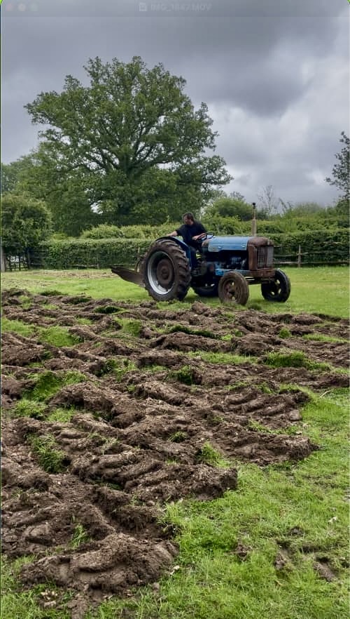 photo of an old blue tractor ploughing a field