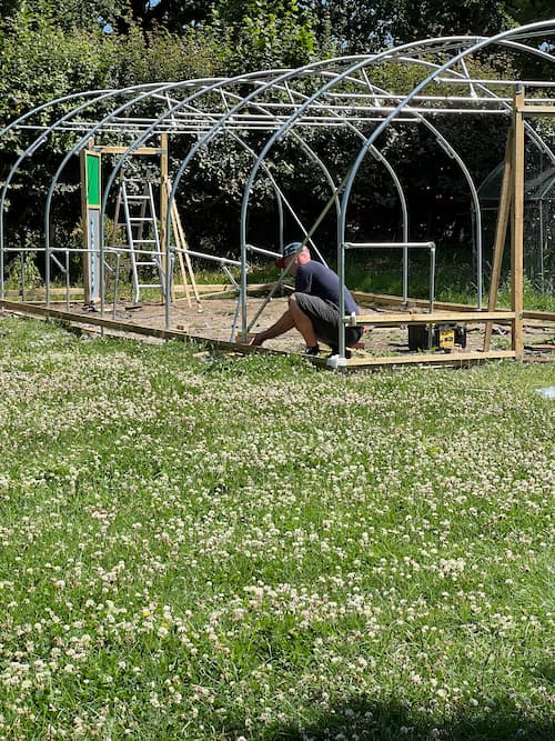 photo of person working on attaching side rails to high tunnel frame